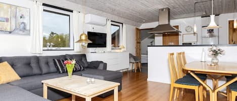 A modern living room with a sofa, coffee table, and dining area with chairs.