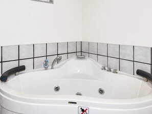 A white bathtub with a digital control panel, a single faucet, and a 'BATH DELUXE' label.