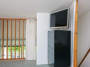 A room with a sliding glass door leading to a balcony, a television on a cabinet, and a small desk with a chair. - 8 Person Holiday Home in Ringkobing (Ringkobing)