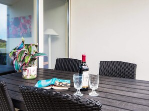A table with a bottle of wine, two glasses, a magazine, and a potted plant. - 8 Person Holiday Home in Ringkobing (Ringkobing)