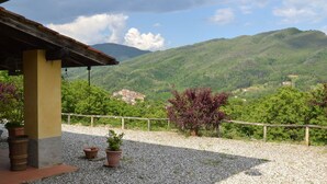 A building with a rustic roof, a gravel patio, and potted plants.