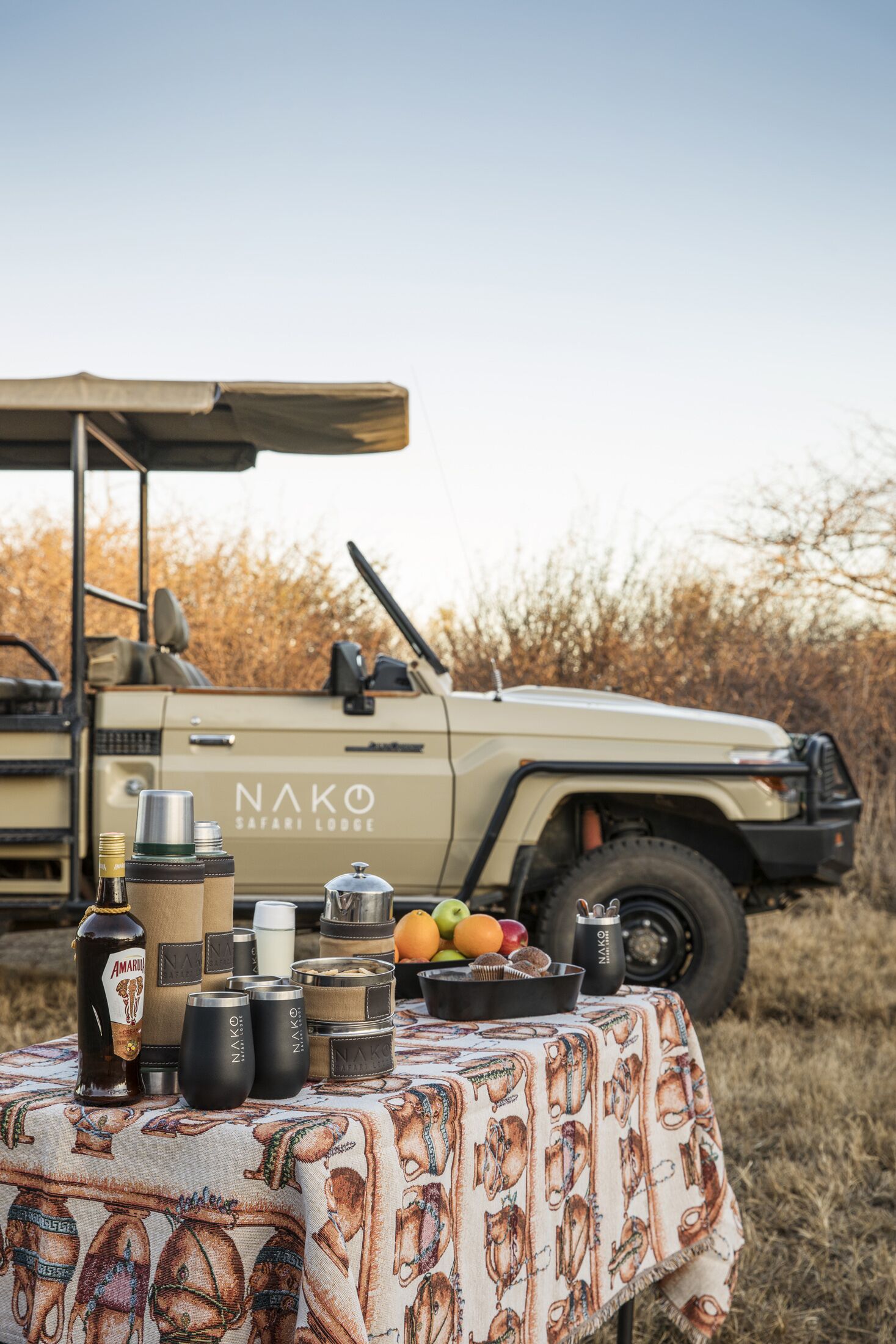 A safari vehicle with a table set for a meal, featuring various containers and fruits.
