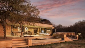 Ein modernes Haus mit großzügigem Außenbereich, das einen Pool, Sitzgelegenheiten und eine Grillzone bietet.