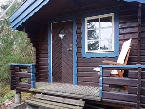 A wooden cabin with a front door, a window, and a porch with a bench. - 4 Star Holiday Home in Ingaro (Ingaro)