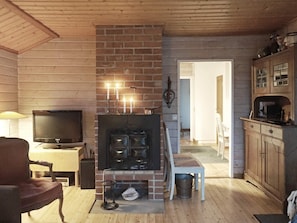 Una sala de estar acogedora con chimenea, televisor y techo de madera.