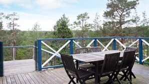 Eine Holzterrasse mit Tisch und Stühlen, umgeben von einem blauen Geländer.
