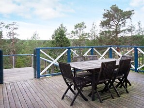 A wooden deck with a table and chairs, surrounded by a blue railing. - 4 Star Holiday Home in Ingaro (Ingaro)