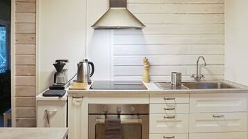 A compact kitchen with a stove, oven, sink, and a coffee maker.