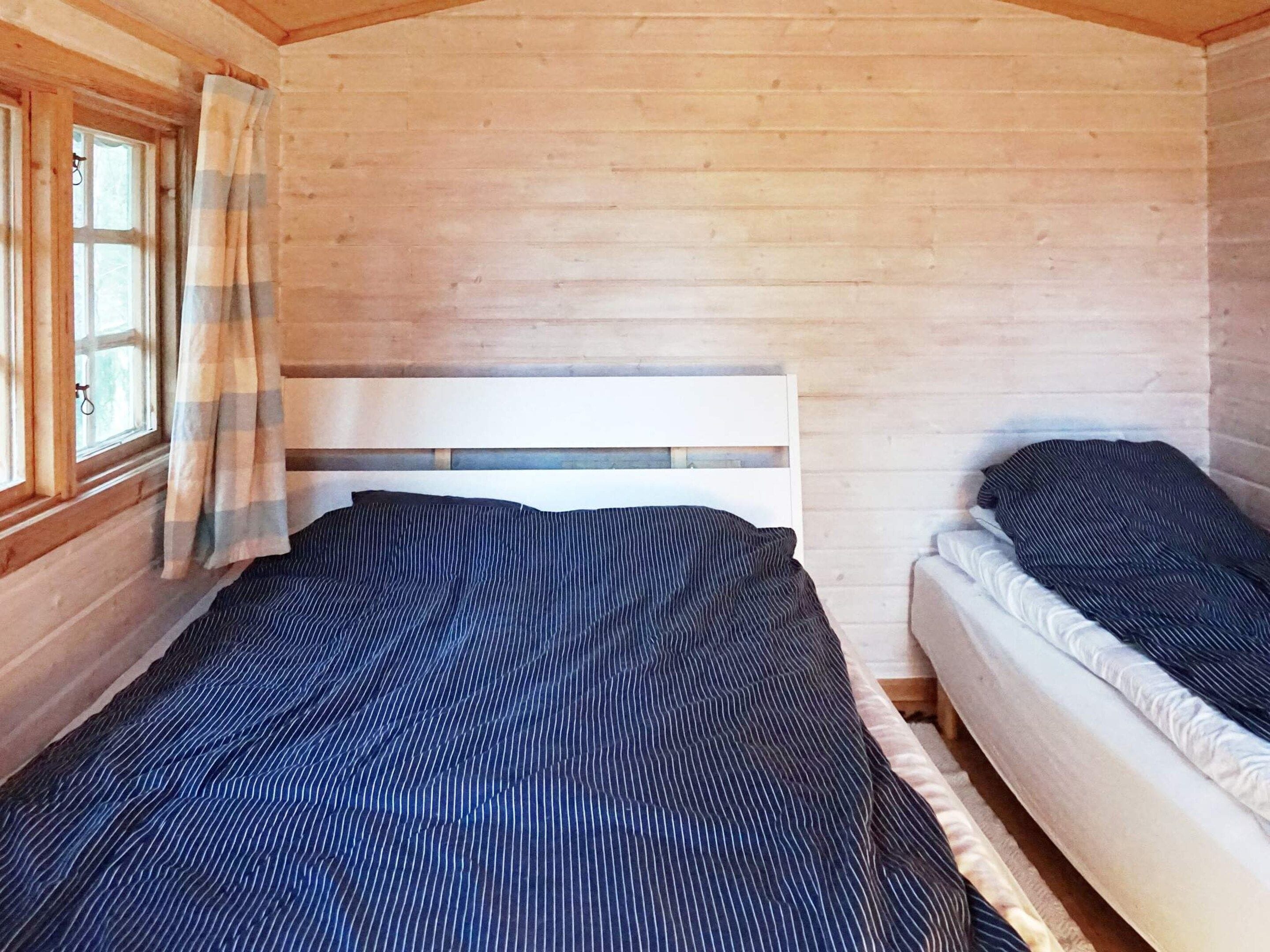 A wooden cabin room with a bed and a small sofa.