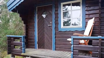 A wooden cabin with a front door, a window, and a bench outside.