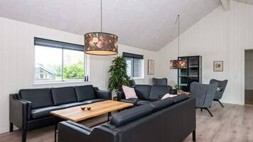 A modern living room with a sectional sofa, a wooden coffee table, and a large window.