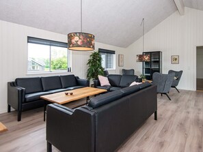 A modern living room with a sectional sofa, a wooden coffee table, and a large window. - 5 Star Holiday Home in Sydals (Sydals)
