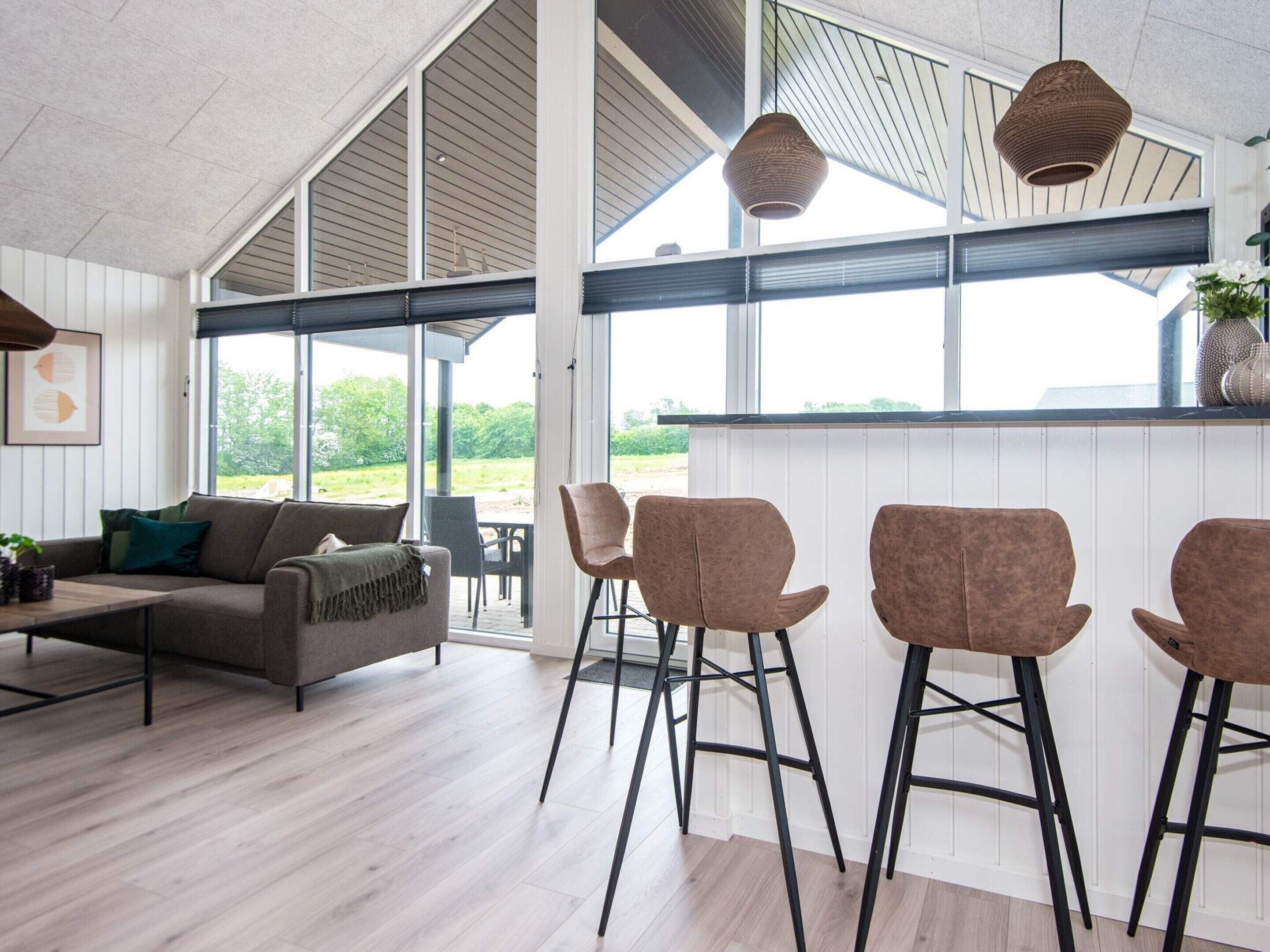 A modern interior with a sofa, chairs, and a dining area with a view.