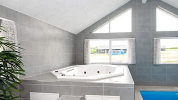 A modern bathroom with a large bathtub, a shower, and a window providing a view of the outside.