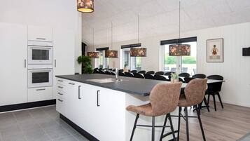 Een moderne keuken met een centraal kookeiland, barkrukken en hanglampen.