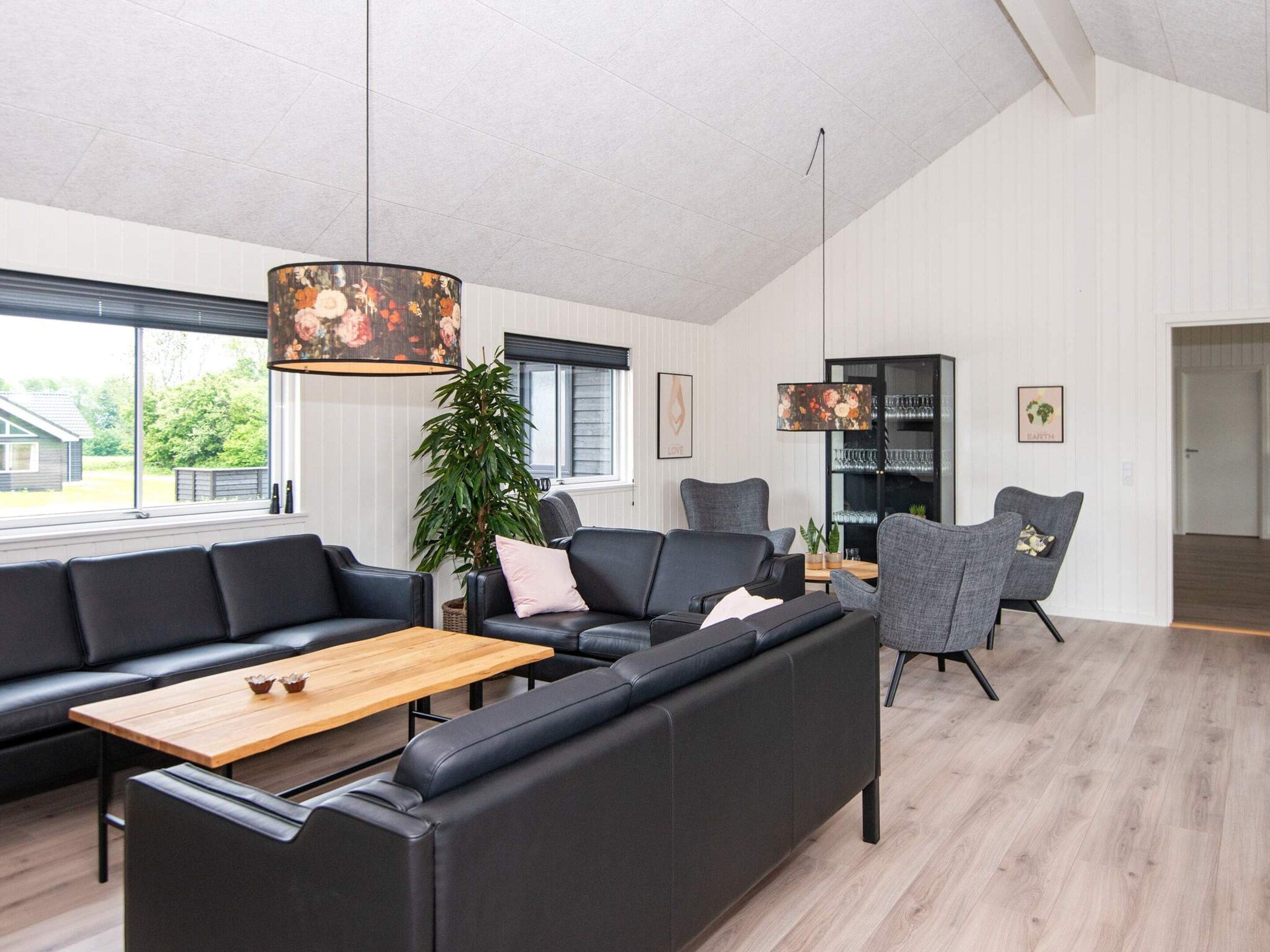 Un salon moderne avec un canapé d’angle, une table basse et une table à manger. Une grande fenêtre laisse entrer la lumière naturelle et offre une vue sur l’extérieur.