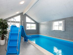 Ein Hallenbad mit blauer Rutsche, Kachelwänden und einem Blumentopf.