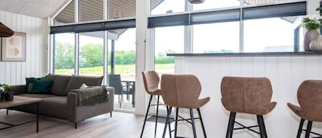 A modern interior with a sofa, chairs, and a dining area with a view.