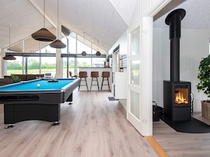Een modern interieur met een pooltafel, bar en een houtgestookte kachel.