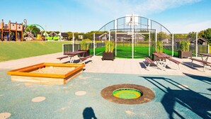 A playground with a fenced play area, benches, and a sandbox. - 5 Star Holiday Home in Sydals (Sydals)