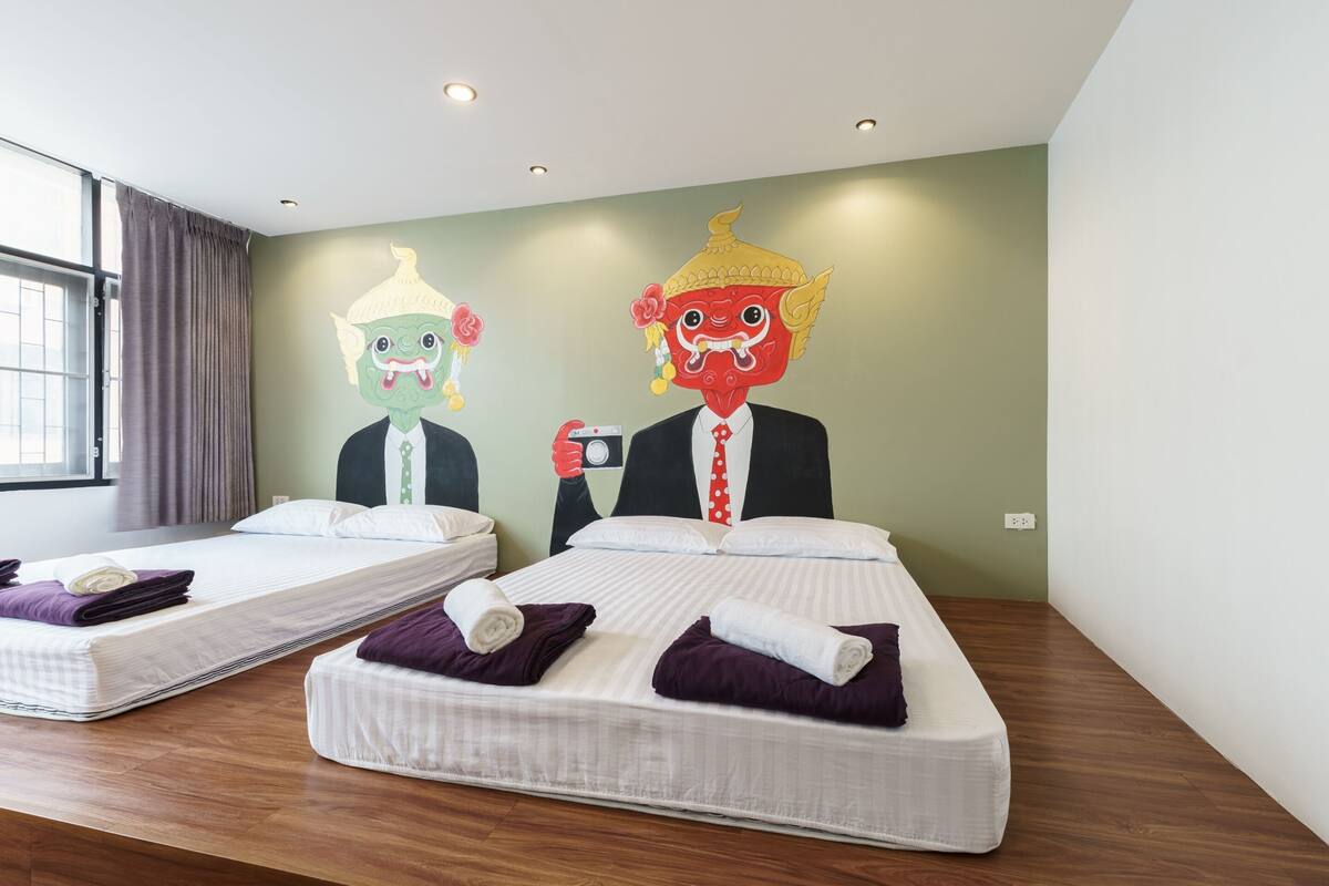 A hotel room with two beds, each with a purple towel and a white pillow.