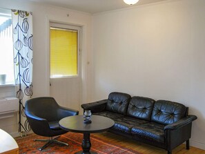 A room with a black leather sofa, a black armchair, and a small round table.
