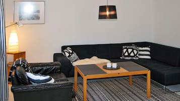 A modern living room with a black sofa, a wooden coffee table, and a striped rug.