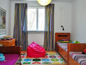 A room with two wooden beds, a bean bag chair, a colorful rug, a window with curtains, and a wall-mounted lamp. - 4 Star Holiday Home in Vittsjo (Vittsjo)