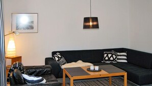 Un salon moderne avec un canapé en cuir noir, une table basse en bois et un tapis à motifs.