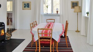 Une salle à manger avec une table ronde, des chaises, une cheminée et une fenêtre avec des rideaux.
