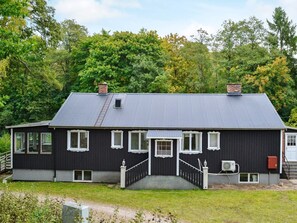 A black house with a grey roof, white windows, and a small porch. - 4 Star Holiday Home in Vittsjo (Vittsjo)