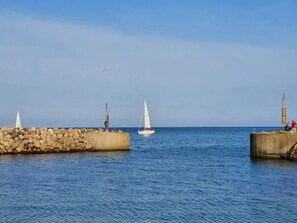A calm sea with a sailboat and a lighthouse in the distance. - 8 Person Holiday Home in Albaek (Aalbaek)