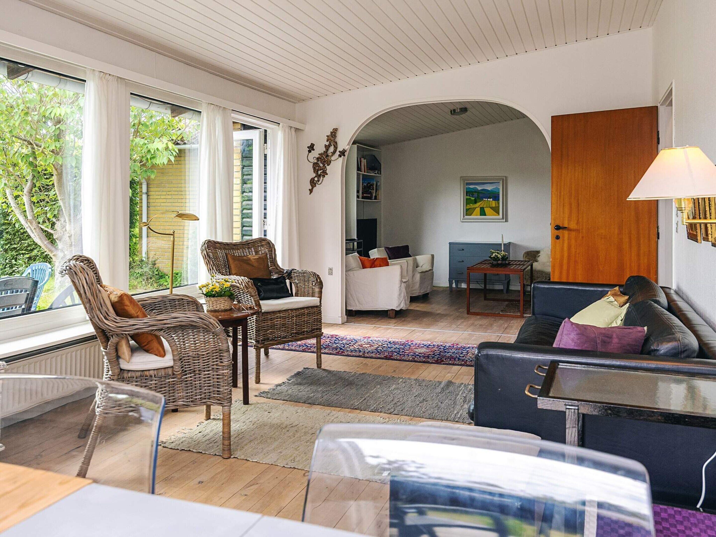 A living room with wicker furniture, a sofa, a coffee table, and a fireplace.