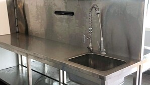 A stainless steel kitchen with a single sink, a faucet, and a soap dispenser.