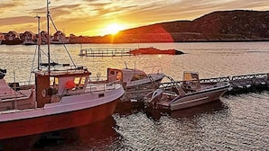 A harbor with boats docked at a pier during sunset.