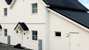 A white building with a black roof, multiple windows, and a door.