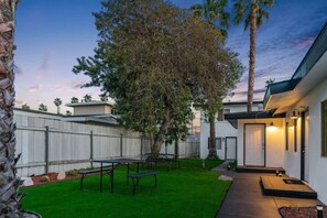 A modern house with a well-maintained lawn, a patio with a table and benches, and a large tree providing shade. - Coastal 2BR Escape with High-Speed WiFi (San Diego)