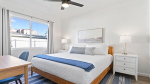 A hotel room with a large bed, two bedside tables, a desk, and a ceiling fan. - Coastal 2BR Escape with High-Speed WiFi (San Diego)