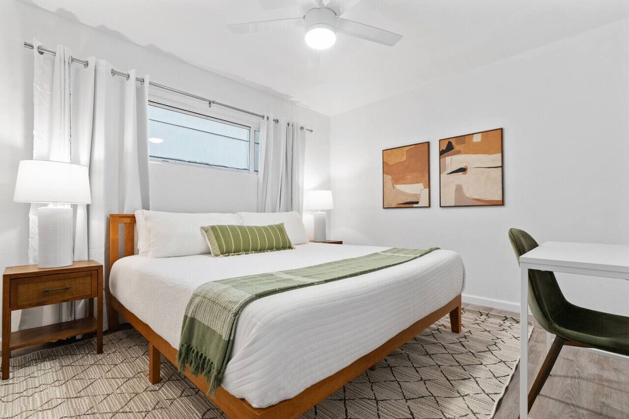 A bedroom with a bed, bedside tables, a desk, and a chair.