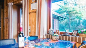 A dining area with a table covered in a colorful tablecloth, a bottle of wine, and various decorative items.