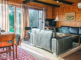 A cozy living room with a sofa, a television, and a dining area with a table and chairs.