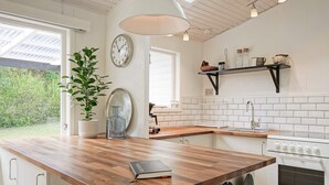 A modern kitchen with a wooden island, white cabinetry, a built-in oven, and a hanging light fixture. - 6 Person Holiday Home in Allinge (Allinge)