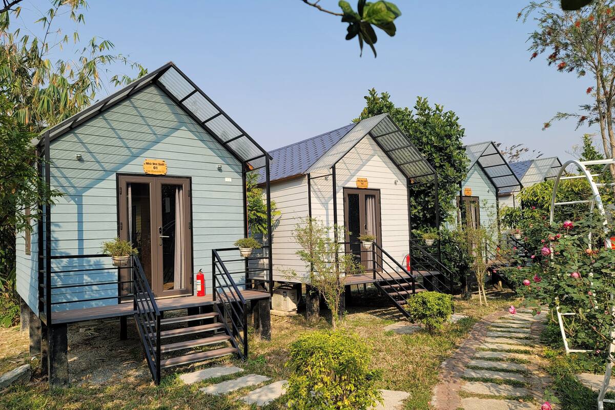 A row of small, light blue cabins with external staircases and potted plants.