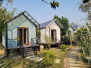 A row of small, light blue cabins with external staircases and potted plants.