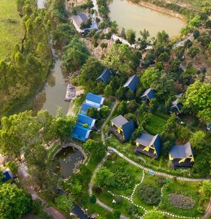 An aerial view of a residential area with houses, a pond, and a well-maintained garden.