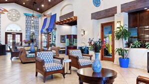 A spacious lobby with a reception desk, seating area with patterned chairs, a decorative fountain, and potted plants. - Luxury Contemporary Style House on Paradise Palms Resort, Orlando House 6144 (Kissimmee)