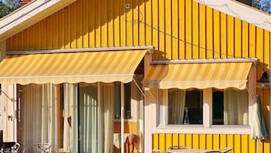 A yellow building with a covered patio area, a table, and chairs. - 4 Star Holiday Home in Ljusdal (Ljusdal)