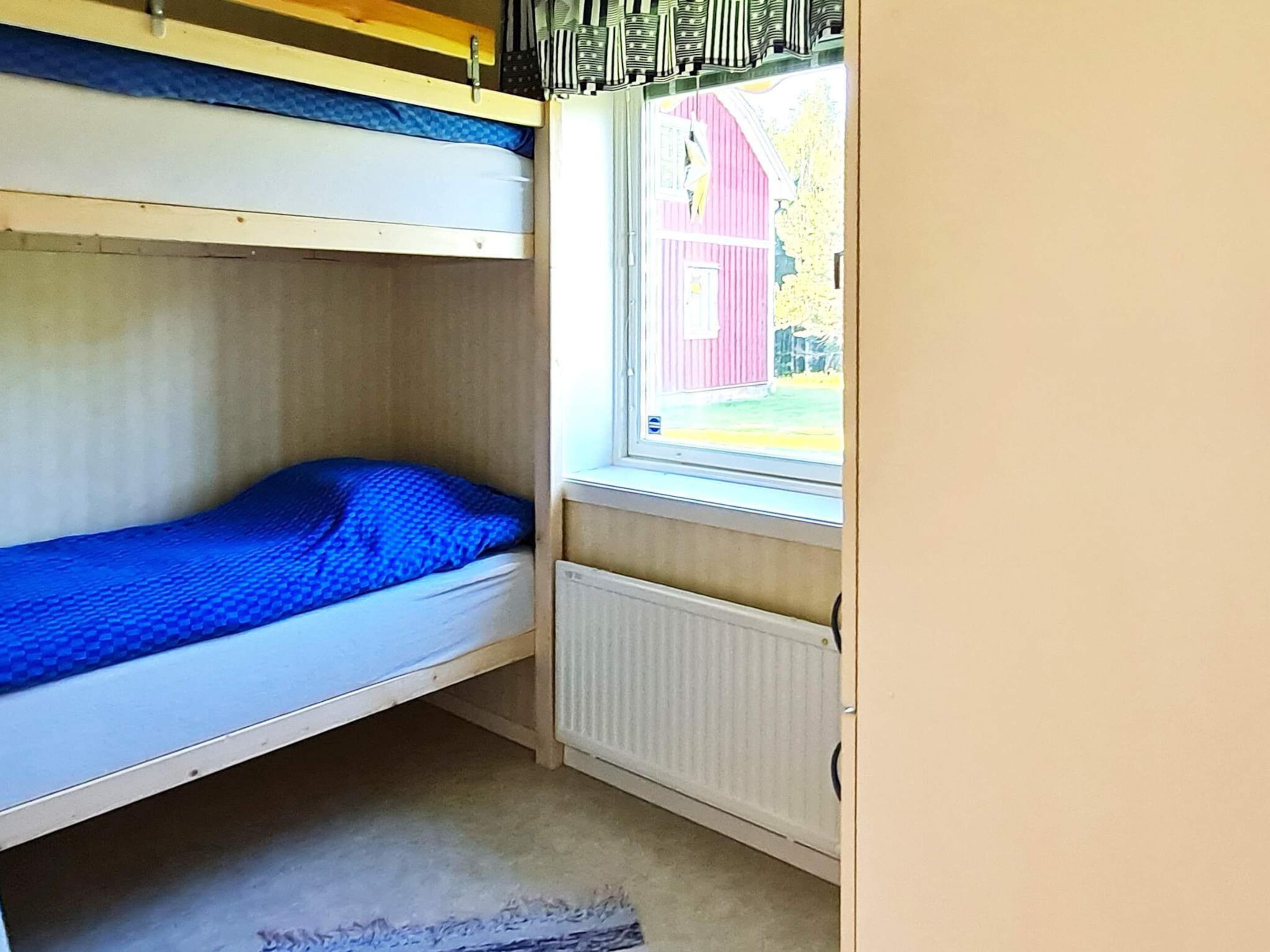 A bunk bed room with a window overlooking a red barn.