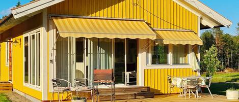 A yellow building with a covered patio, large windows, and outdoor seating.