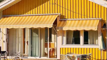 A yellow building with a covered patio area, a table, and chairs.
